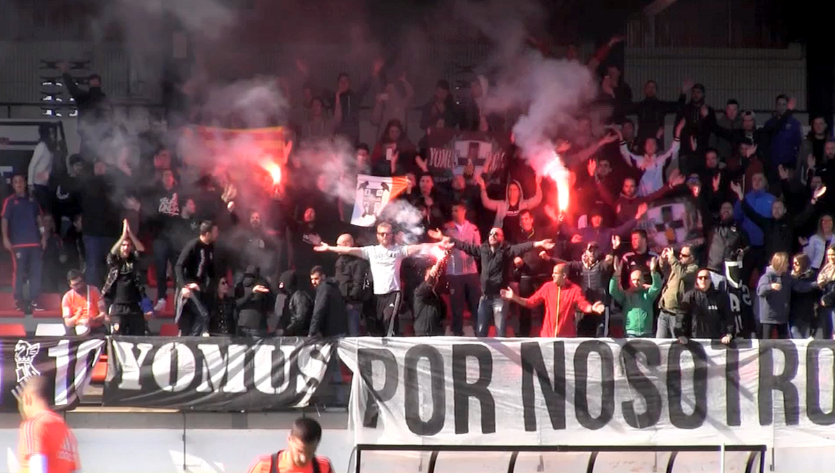 Ultras Yomus con bengalas y pancarta en una grada visitante